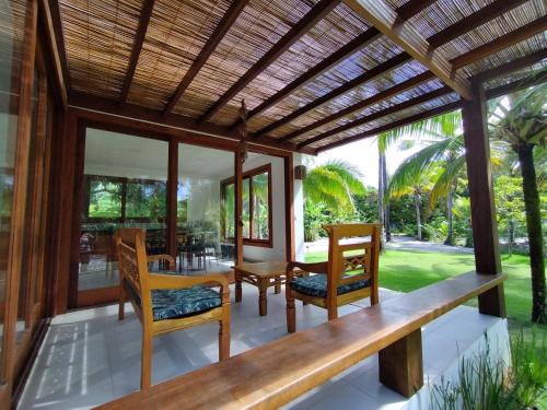 a patio with chairs and a wooden pergola at Kíria's Village Beach House in Marau