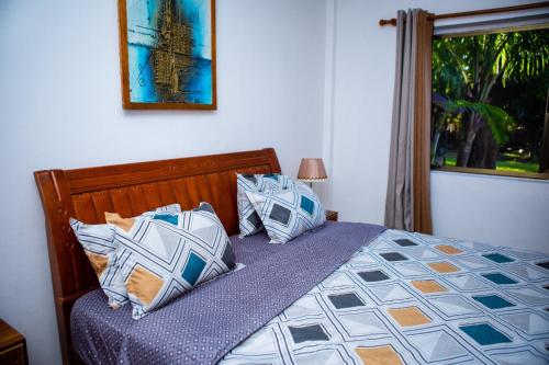 - une chambre avec un lit doté d'oreillers bleus et blancs dans l'établissement Luxor garden apartments, à Accra