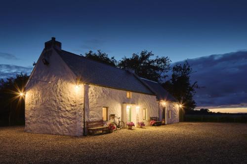 a white building with lights on the side of it at Maggie Deenys Cottage in Lackagh