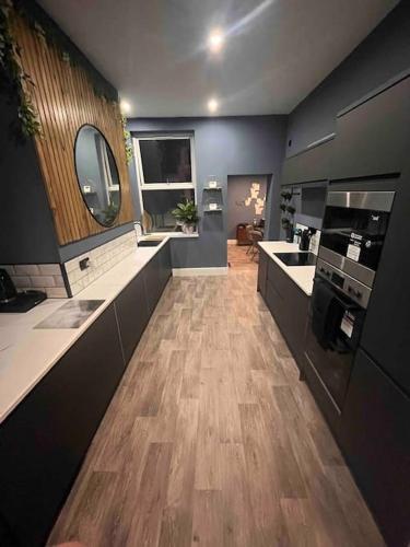 a large kitchen with wooden flooring and a kitchen with counters at Modern 5 Bedroom Terraced Luxurious House in Colwyn Bay
