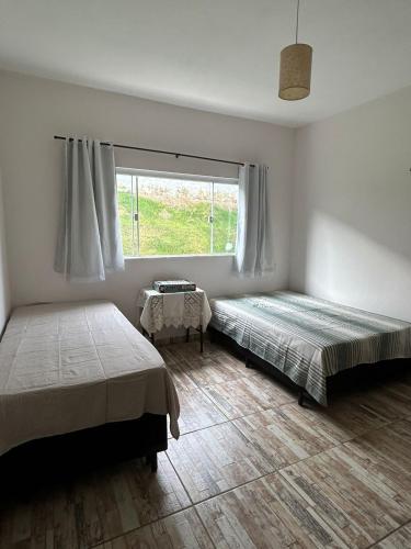 a bedroom with two beds and a window at Recanto Vó Rosa in Socorro