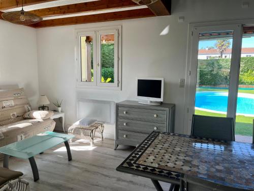 Villa Bleu soleil في بورنيك: غرفة معيشة مع تلفزيون وأريكة وطاولة