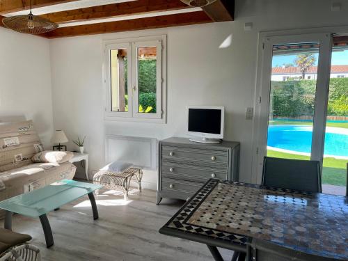 un salon avec une télévision, un canapé et une table dans l'établissement Villa Bleu soleil, à Pornic