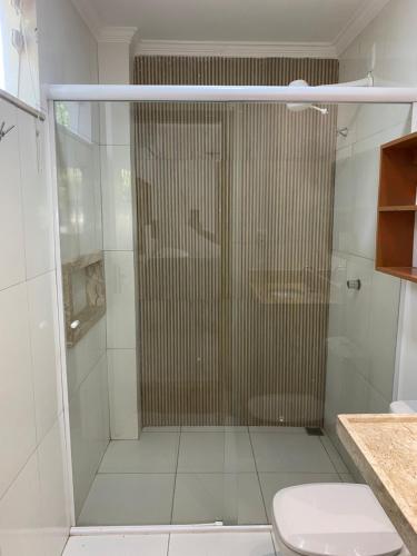 a bathroom with a glass shower with a toilet at Pousada Casa Dunas in Barreirinhas