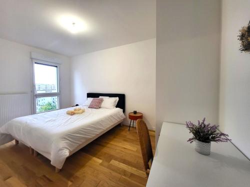 a bedroom with a bed and a table and a window at Le Lucie - Bain de lumière au pied du métro in Bagneux
