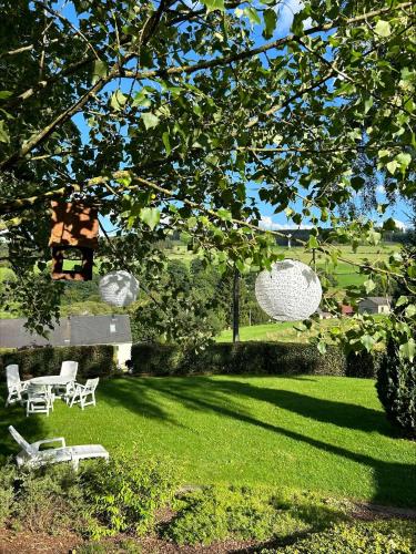 a yard with two chairs and a table and a tree at Chalet Panor'Anna in Saint-Vith