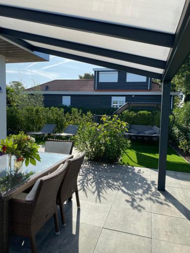 a patio with a table and chairs under a pergola at LUXUS Cube Ferienhaus Chalet am See mit Schwimmbad in Lathum NL in Lathum