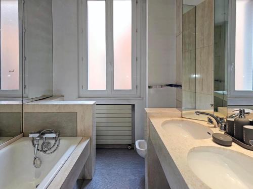 a bathroom with two sinks and a bath tub at L'Idrac, Appartements en Hyper centre in Toulouse