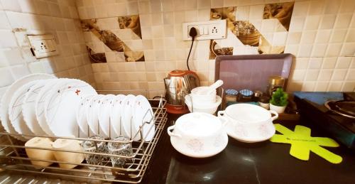 a kitchen counter with dishes and a rack of dishes at Boutique Stay for Family On Manali Expressway in Lāndrān