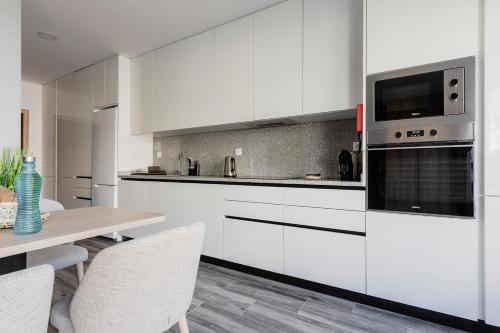 a kitchen with white cabinets and a table with chairs at Blue Apartments in Leiria