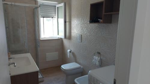 een badkamer met een toilet, een wastafel en een raam bij Villa SereMar in Pulsano