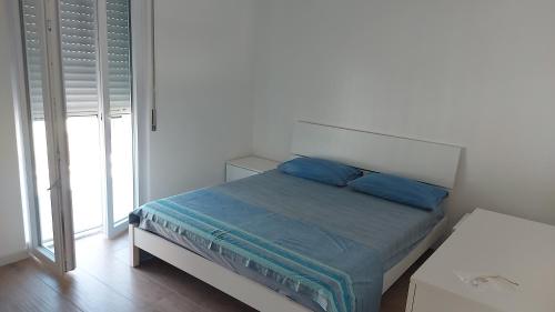 een bed met twee blauwe kussens in een witte kamer bij Villa SereMar in Pulsano