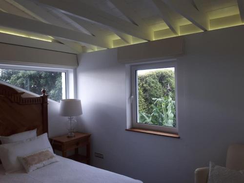 un dormitorio con una cama y una ventana en Quinta do Avô, en Ribeira das Tainhas