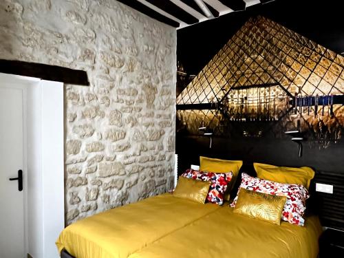 - une chambre avec un lit jaune et un mur en pierre dans l'établissement MARAIS Appartement 2 Chambres 2 Salles de bain - SPA JACUZZI !, à Paris