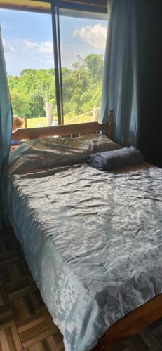 Bett in einem Zimmer mit einem großen Fenster in der Unterkunft Cabaña de la Montaña in Río Cuarto