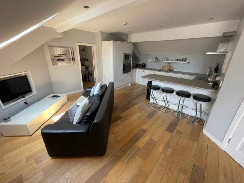ein Wohnzimmer mit einem schwarzen Sofa und einer Küche in der Unterkunft Fernside Barn Apartment in Pickmere