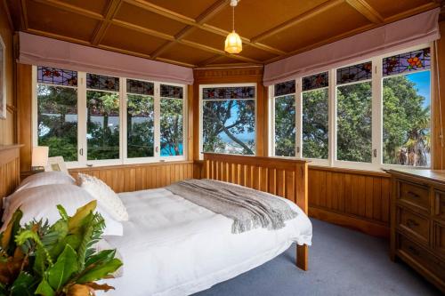 1 dormitorio con 1 cama blanca y algunas ventanas en Historic Homestead, en Napier