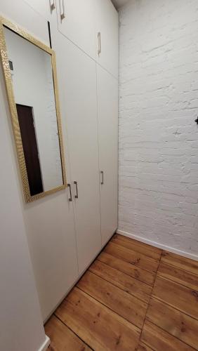 a room with white walls and a mirror and wooden floors at Klimatyczny apartament w sercu Bydgoszczy in Bydgoszcz
