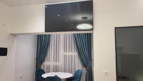 een tv aan een muur met een tafel en twee stoelen bij Karanxha's room in Tirana