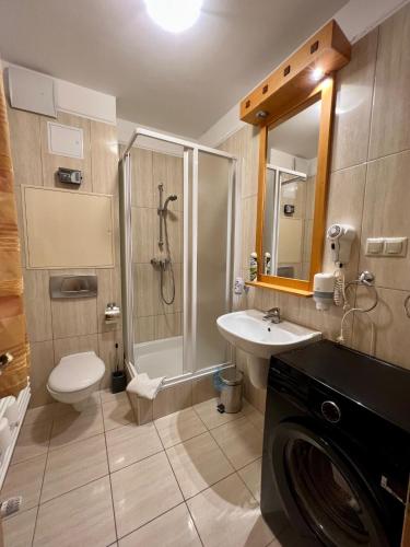 a bathroom with a shower and a toilet and a sink at Luxus Golf Apartment in Bük