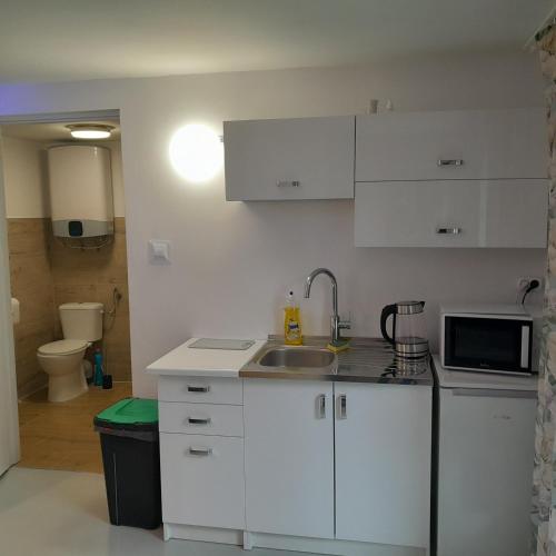 una cucina bianca con un lavello e un forno a microonde di Domek Muchorek 1km od Energylandii a Zator