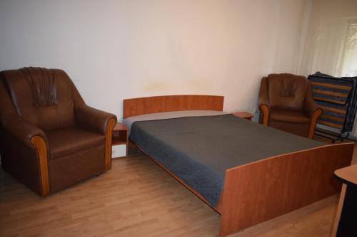 a bedroom with two chairs and a bed with a bedspread at Apartament Modest Traian RHBM in Baia Mare