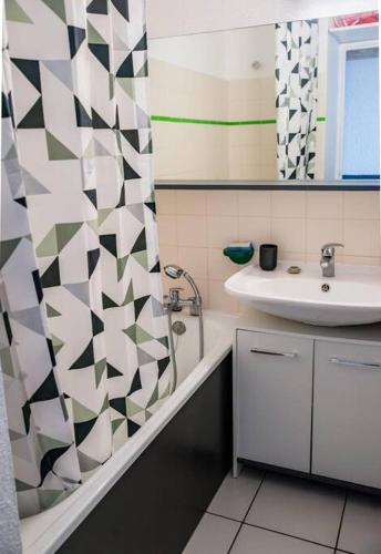 une salle de bain avec un lavabo et un rideau de douche dans l'établissement Appartement avec vue magnifique sur le lac marin, au Barcarès