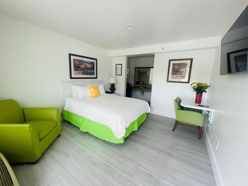 a hotel room with a bed and a green chair at Loma Linda Inn in San Bernardino