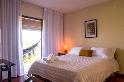 a bedroom with a bed and a large window at Hidromassagem, 5 qtos, 3 stes com vista para a Pedra Azul - Adelta hospedagem in Venda Nova do Imigrante