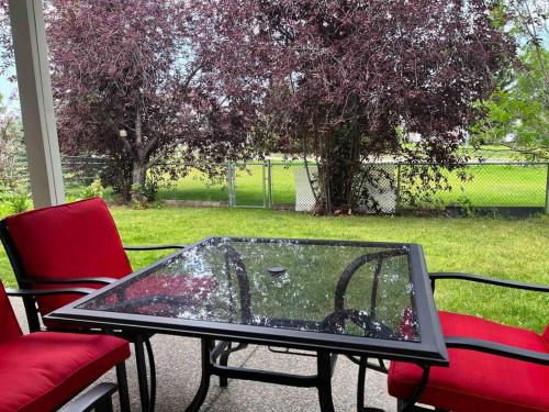 a glass table and two chairs on a patio at Cozy Walkout suite with King bed, Kitchen, Parking & Patio in Calgary