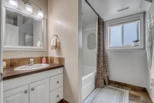 a bathroom with a sink and a shower at Registered Renovated walkout suite with King-bed, Kitchen, Parking, Patio in Calgary