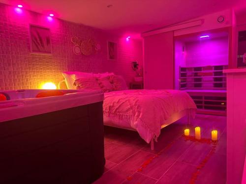 een slaapkamer met roze verlichting, een bed en een bad bij Love room. Une bulle d évasion. in Lisses