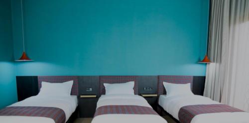 three beds in a room with a blue wall at Green Rooms in Kutaisi