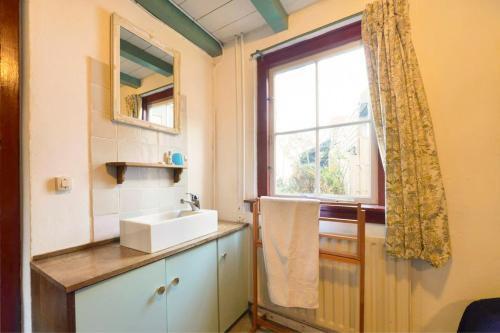 a bathroom with a sink and a window at Rustic Retreat: Fireplace, BBQ, + Forest Access in Burgh Haamstede