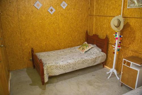 um pequeno quarto com uma cama numa parede amarela em Qintipillpi Lunahuaná em Lunahuaná