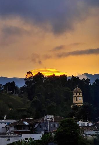 a sunset over a town with a clock tower at Casa Selah - Una pausa entre café y montañas in Salento