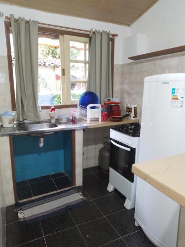 a kitchen with a sink and a refrigerator at Casinha Centro histórico in Paraty