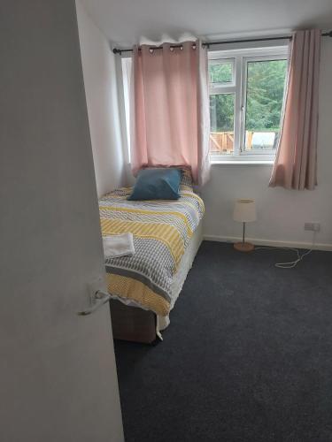 a small bedroom with a bed and a window at super comfortable 3 bed house in Houghton Regis