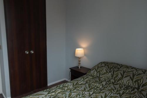a bedroom with a bed and a lamp on a table at Habitaciones en Departamento compartido centro de Viña in Viña del Mar