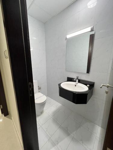 a white bathroom with a sink and a toilet at SIRIUS TOWER in Juffair