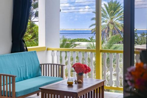 a balcony with a table and chairs and a view of the ocean at Diver's Paradise Bonaire in Kralendijk