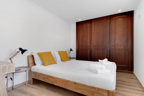 sypialnia z białym łóżkiem i drewnianymi drzwiami w obiekcie Casa Ferrera - Spacious Castle View Village Apt w Aljezur