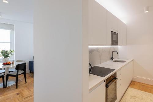 a kitchen with white cabinets and a dining room with a table at FOX ON THE HOE in Plymouth