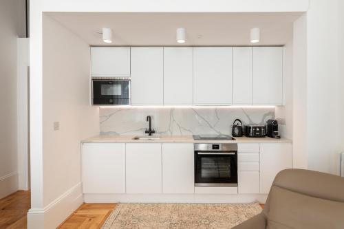 a kitchen with white cabinets and a sink at FOX ON THE HOE in Plymouth