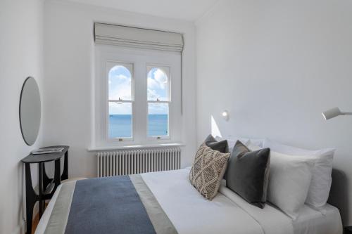 a white bedroom with a bed and a window at FOX ON THE HOE in Plymouth