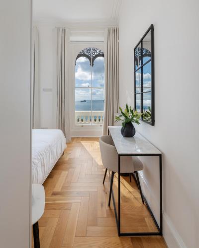 a bedroom with a bed and a table and two windows at FOX ON THE HOE in Plymouth