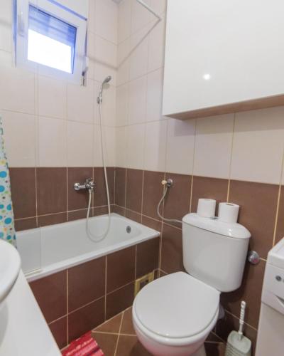 a bathroom with a toilet and a tub and a sink at City Center Family Apartment Novi Sad in Novi Sad