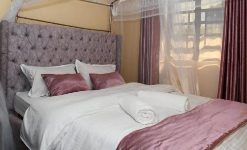 een slaapkamer met een groot bed met witte lakens en kussens bij Intellicents Apartments in Kisumu