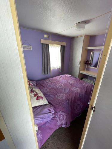 a small bedroom with a purple bed in it at Tessas caravan breaks in Chapel Saint Leonards