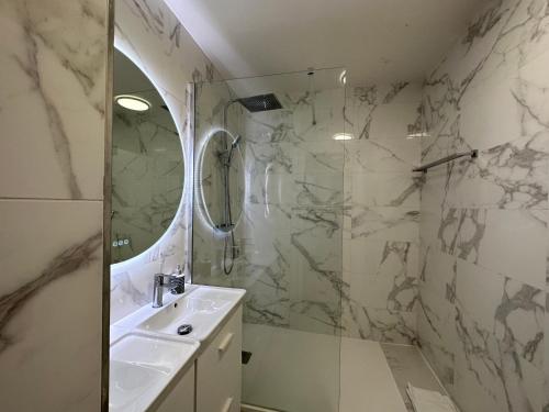 a bathroom with a sink and a shower with a mirror at Appt Vue Place de Toscane - 4min Disneyland-PARIS in Serris